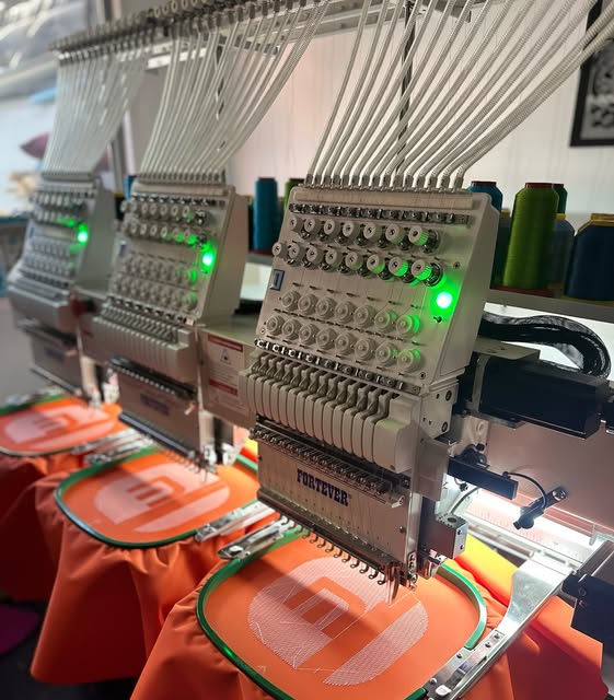 Máquinas bordadoras multicabezal de BordaFast bordando logos en tela naranja